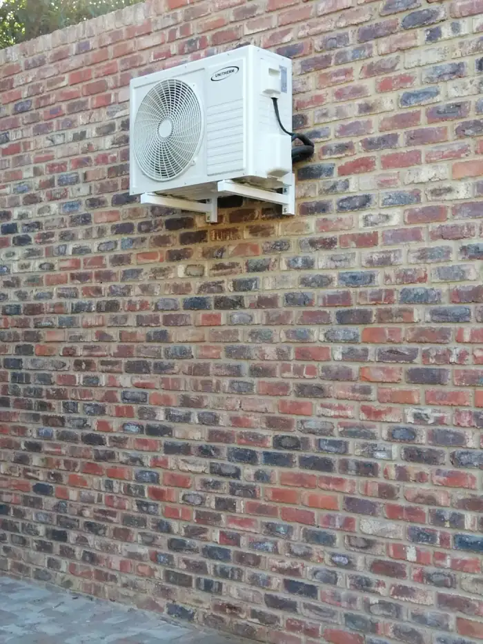 Outdoor unit on a face-brick wall by SJS Cooling