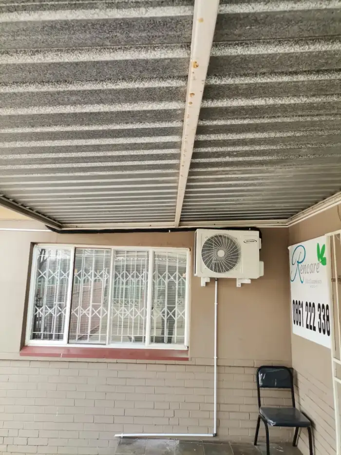 Outdoor unit under a carport roof by SJS Cooling
