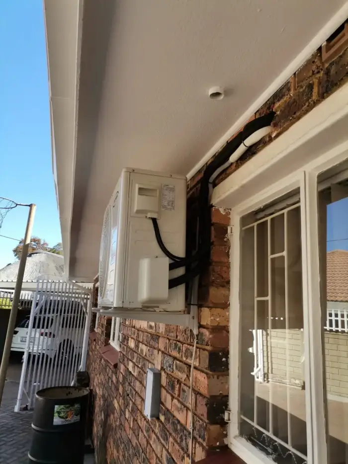 Outdoor unit installed under a patio roof by SJS Cooling