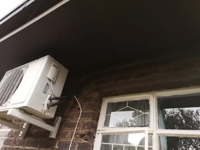 Outdoor unit installed under the eaves by SJS Cooling