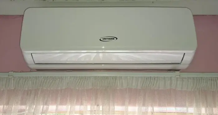 Indoor split unit above a curtained window by SJS Cooling